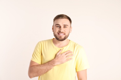 Photo of Young man holding hand on his heart against white background