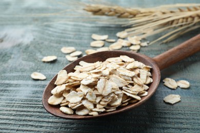 Photo of Spoon with oatmeal on light blue wooden table, closeup