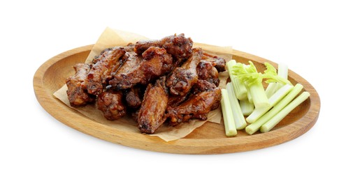 Wooden plate with delicious chicken wings and cut celery stalks isolated on white
