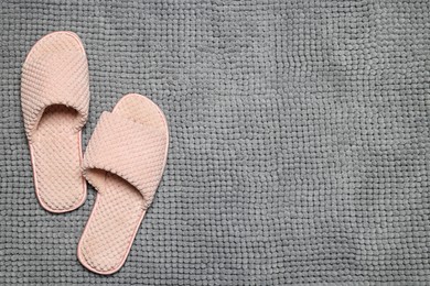 Photo of Slippers on soft grey bath mat, flat lay. Space for text