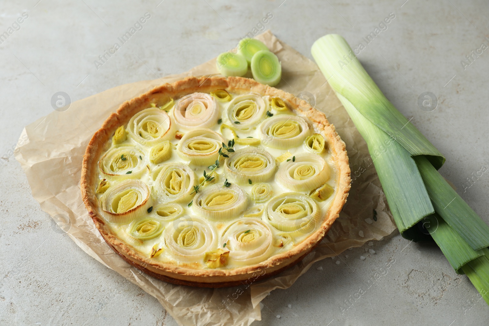 Photo of Tasty leek pie with thyme on grey textured table