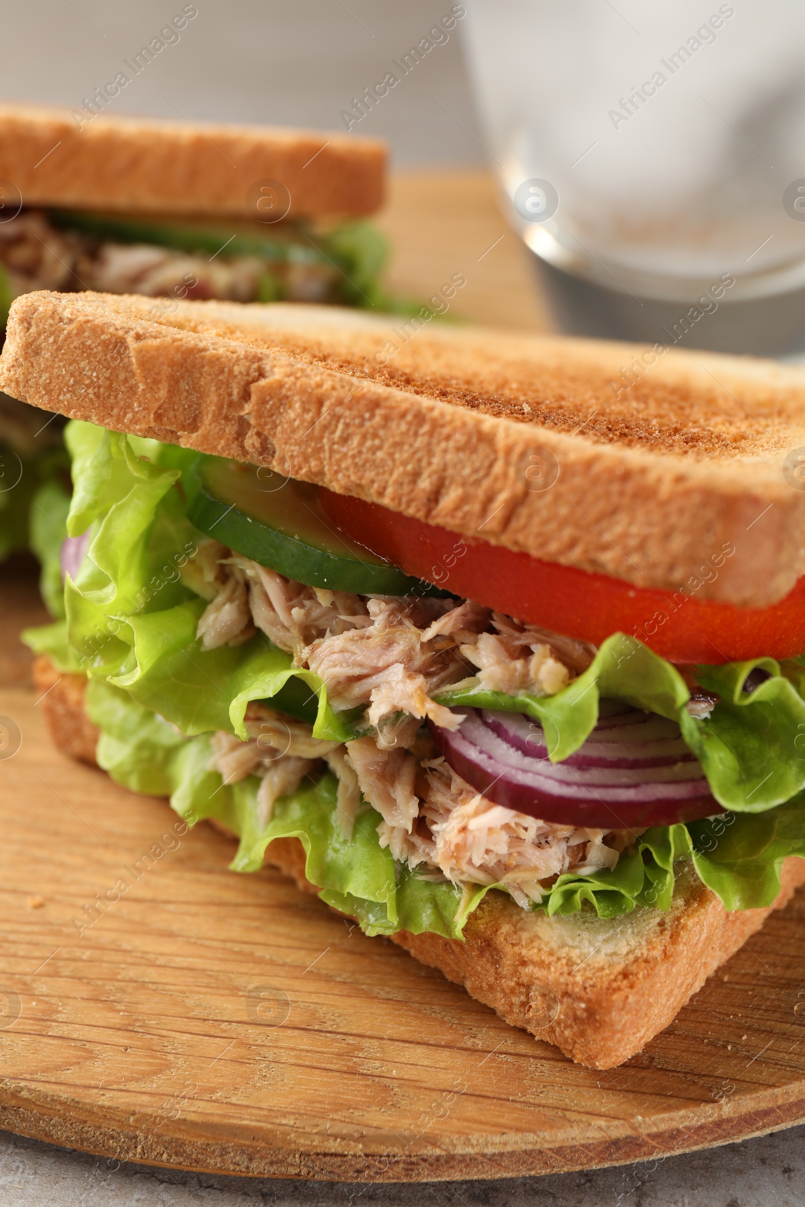 Photo of Delicious sandwiches with tuna and vegetables on wooden board, closeup