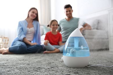 Modern air humidifier and blurred family on background