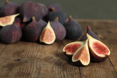 Photo of Whole and cut tasty fresh figs on wooden table, space for text
