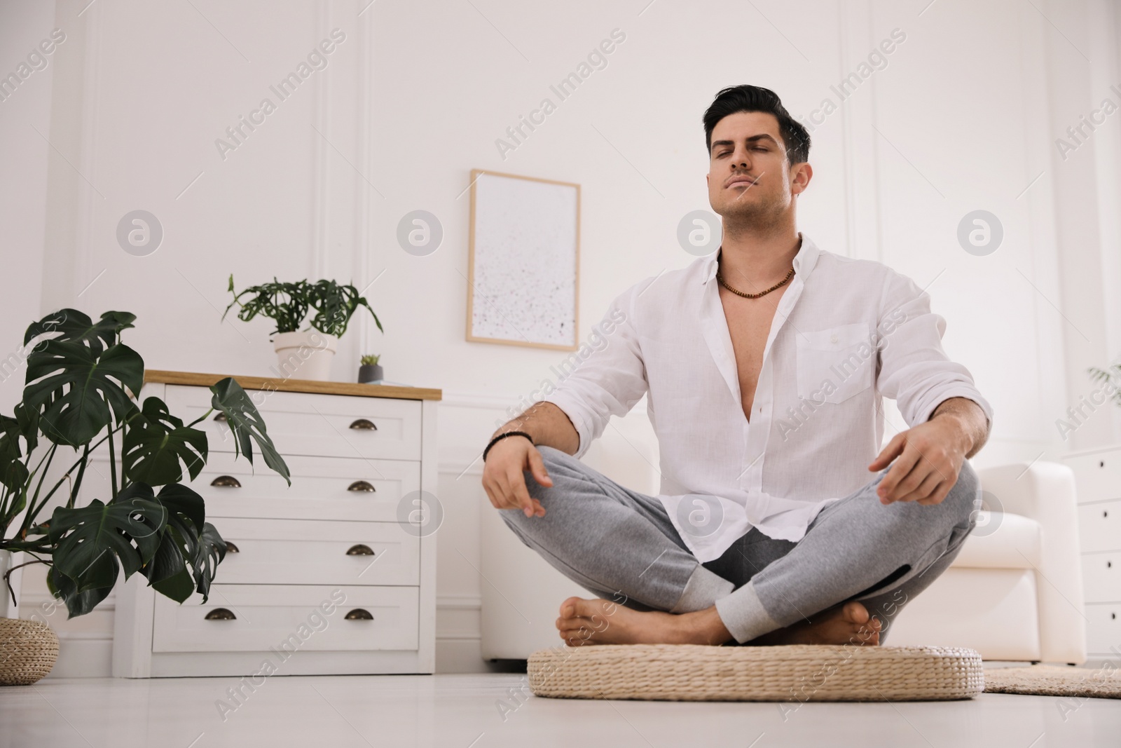 Photo of Man meditating on wicker mat at home. Space for text