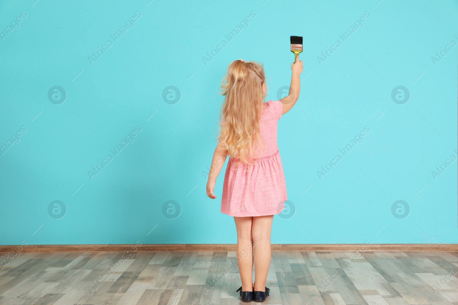 Photo of Little child painting color wall with brush