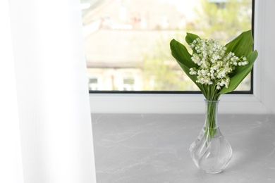 Photo of Beautiful lily of the valley bouquet in vase on windowsill, space for text