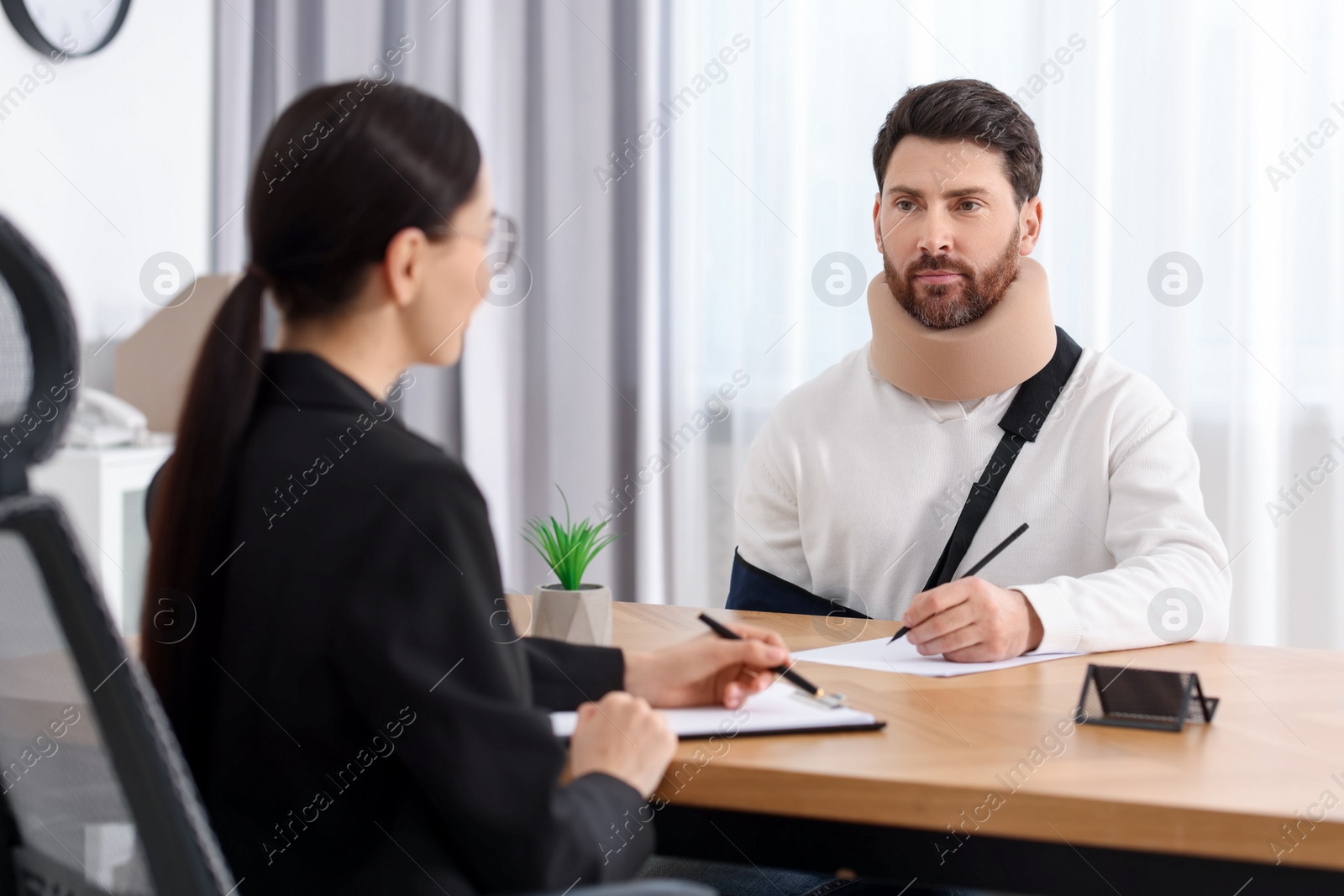 Photo of Injured man signing document in lawyer's office, selective focus