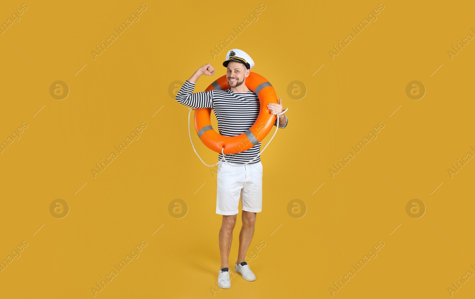 Photo of Sailor with orange ring buoy showing biceps on yellow background