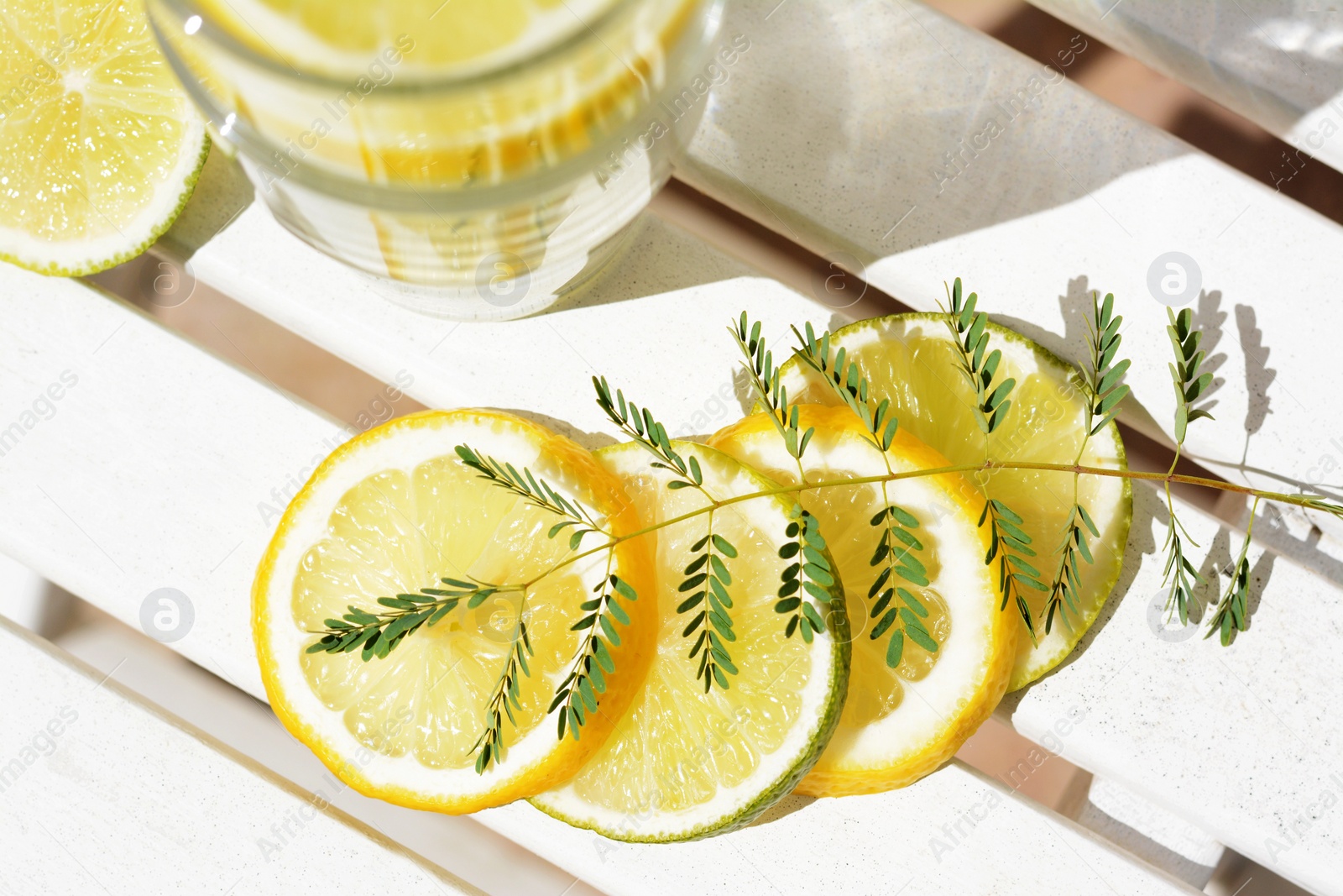 Photo of Delicious refreshing lemonade and pieces of citrus on white wooden table outdoors, flat lay