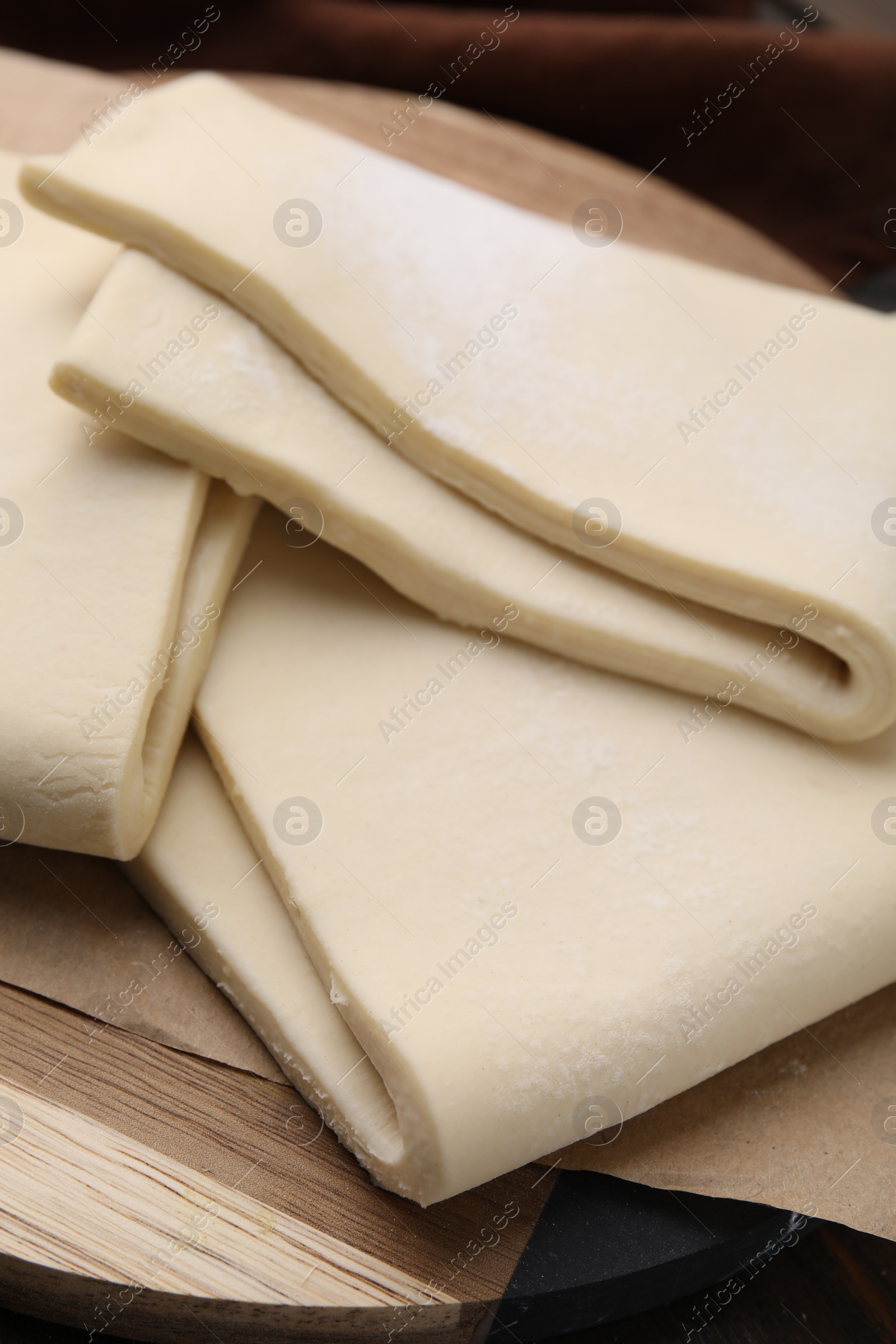 Photo of Raw puff pastry dough on wooden table, closeup