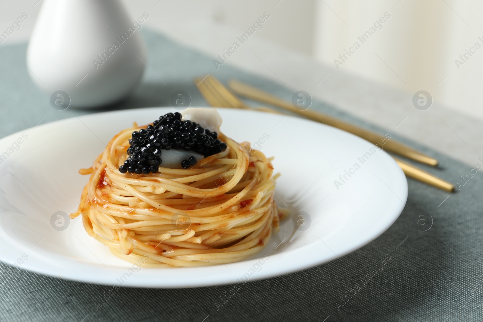 Photo of Tasty spaghetti with tomato sauce and black caviar served on table, closeup. Exquisite presentation of pasta dish