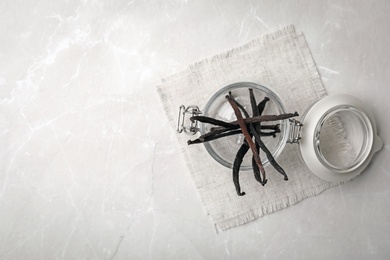 Photo of Jar with aromatic vanilla sticks on grey background