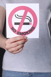 Photo of Woman holding card with no smoking sign, closeup