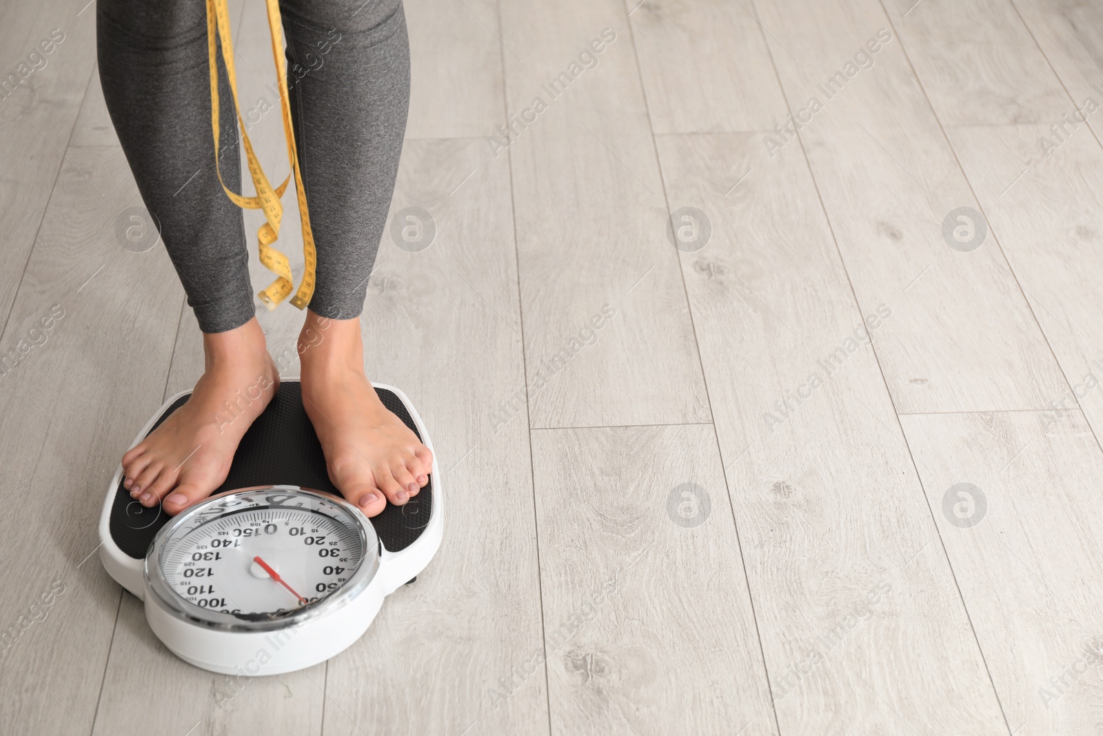 Photo of Woman with tape standing on scales indoors, space for text. Overweight problem