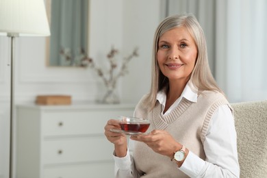 Photo of Portrait of beautiful middle aged woman with cup of tea at home, space for text