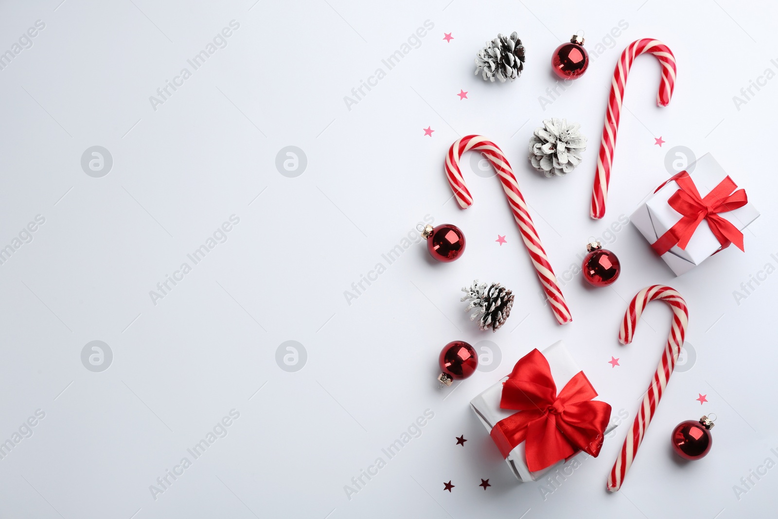 Photo of Flat lay composition with candy canes and Christmas decor on white background. Space for text