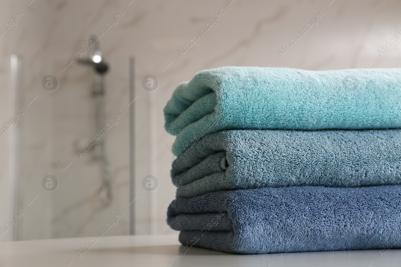 Photo of Stack of clean towels on table in bathroom, closeup. Space for text