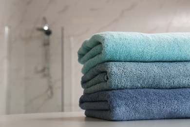 Photo of Stack of clean towels on table in bathroom, closeup. Space for text