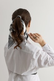 Photo of Young woman with stylish bandana on light background, back view