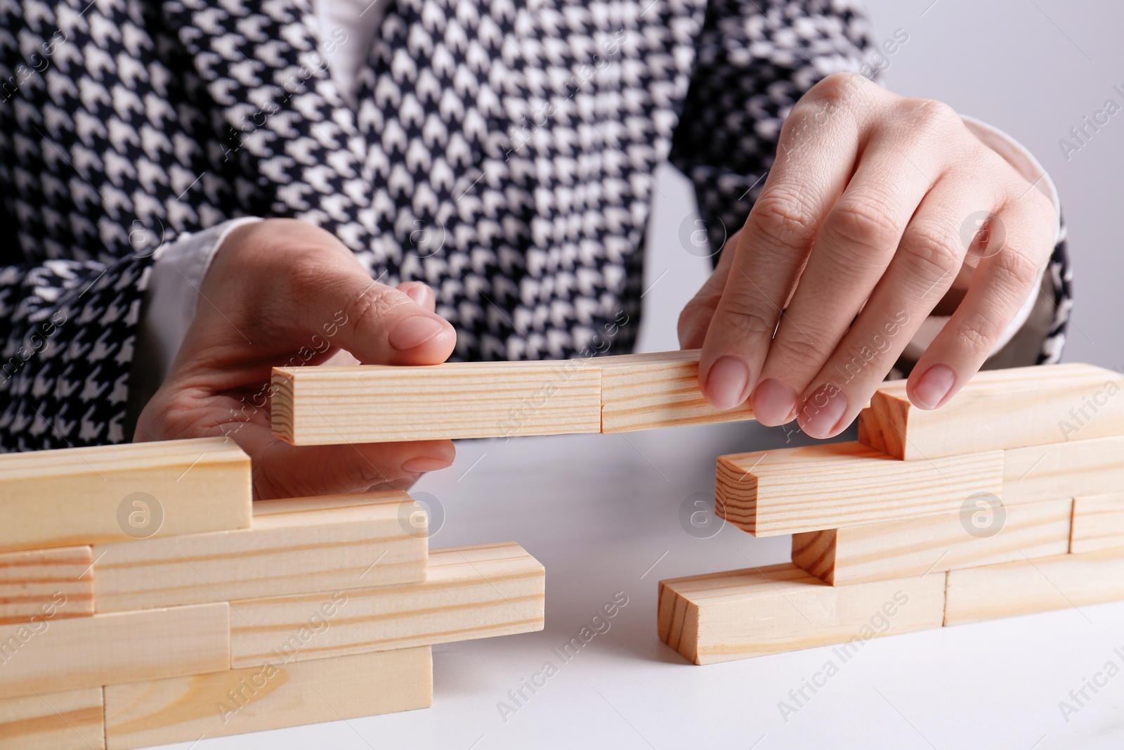 Photo of Businesswoman building bridge with wooden blocks at table, closeup. Connection, relationships and deal concept