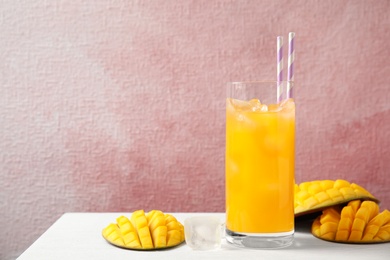 Fresh mango drink and fruits on table against color background. Space for text