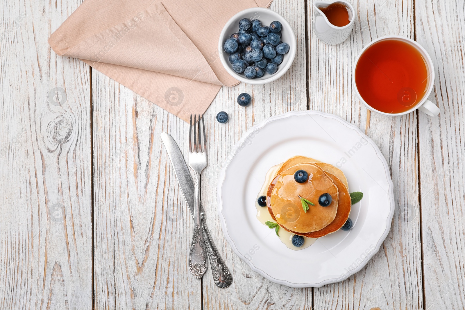 Photo of Flat lay composition with tasty pancakes and cup of tea on wooden background