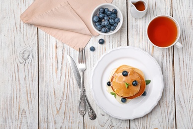 Flat lay composition with tasty pancakes and cup of tea on wooden background