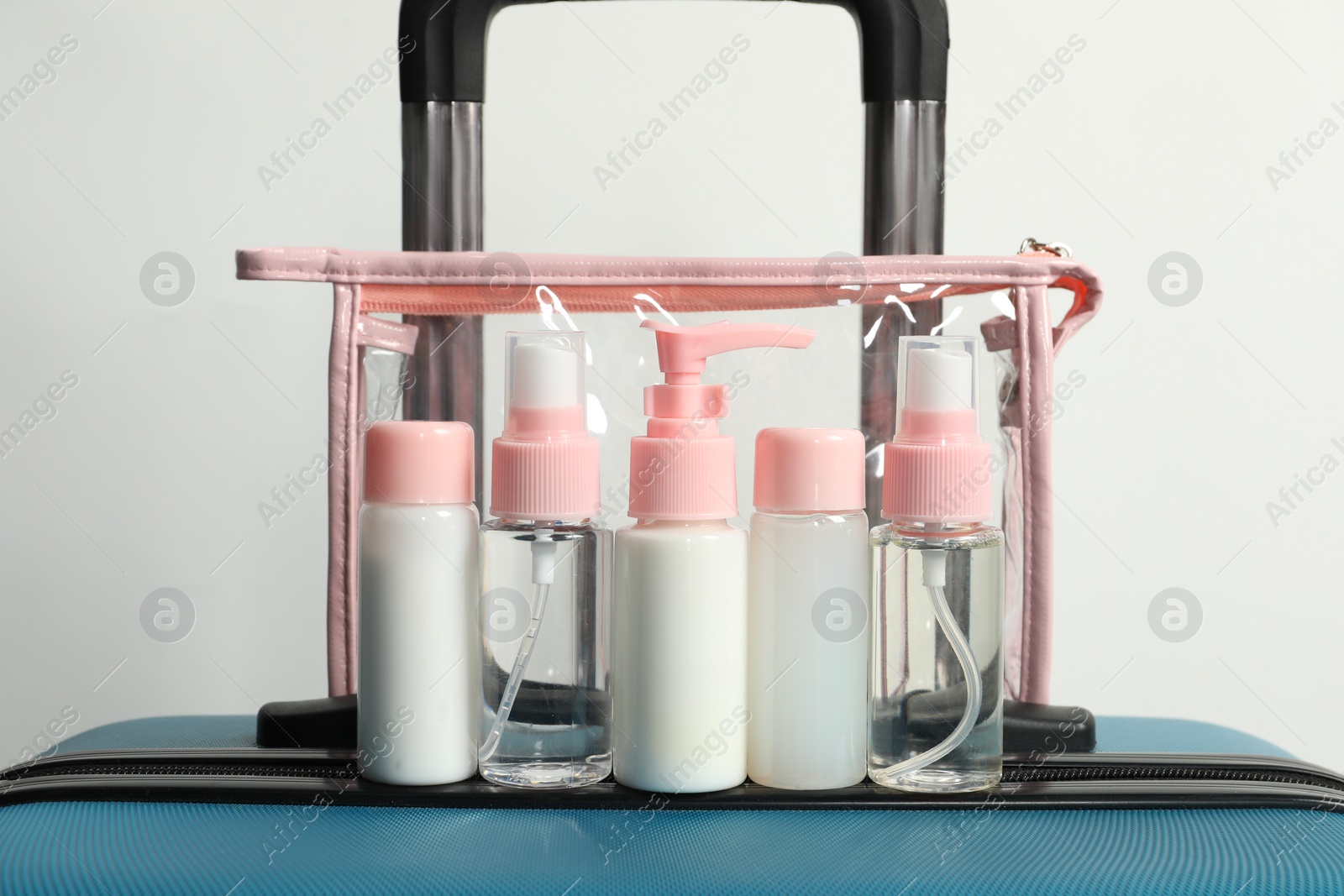 Photo of Cosmetic travel kit in plastic bag on suitcase against light background