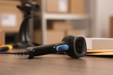 Photo of Black modern barcode scanner on wooden table in office, closeup. Online store