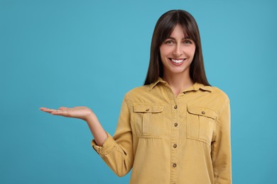 Photo of Special promotion. Happy woman showing something on light blue background, space for text