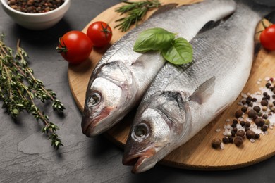 Sea bass fish and ingredients on black table, closeup