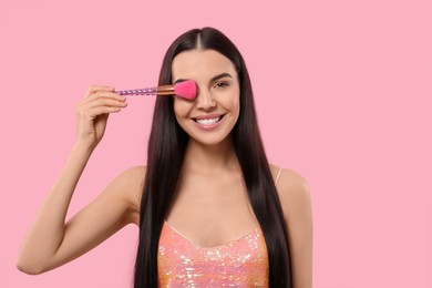 Photo of Beautiful woman with makeup brush on pink background