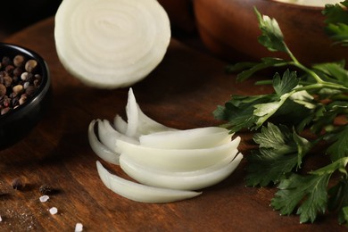 Photo of Cut onion, parsley and pepper on wooden table, closeup