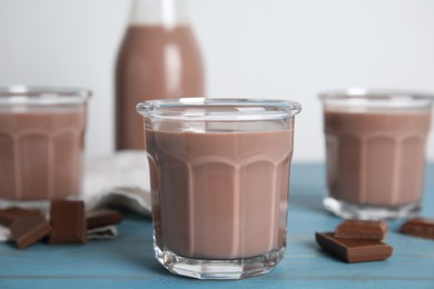 Photo of Delicious chocolate milk on light blue wooden table