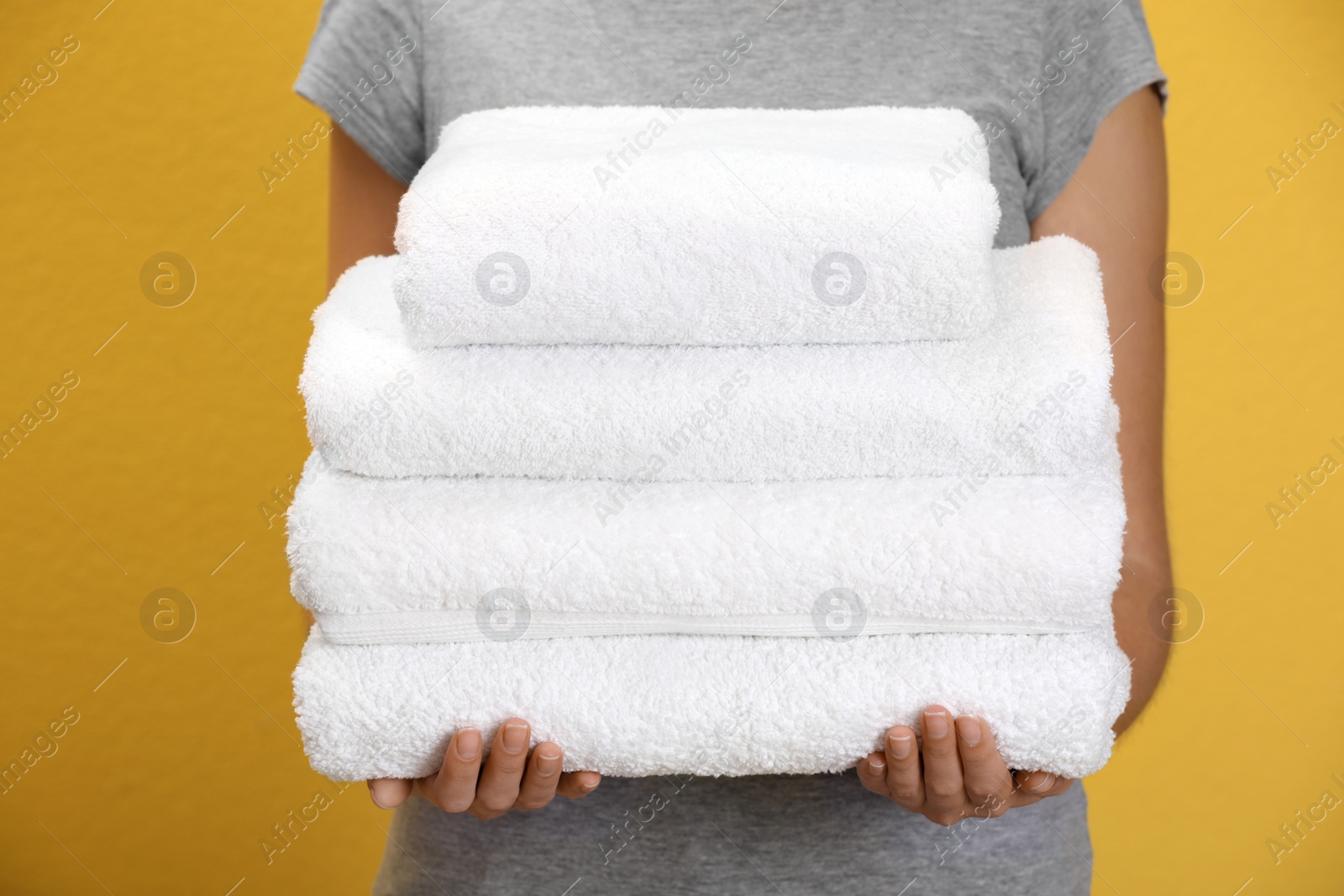 Photo of Woman holding fresh towels on orange background, closeup