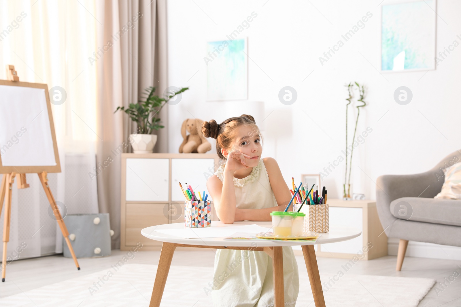 Photo of Child sitting at table with painting tools indoors