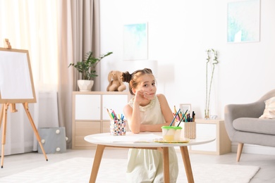 Child sitting at table with painting tools indoors