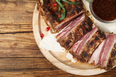 Photo of Delicious grilled ribs served on wooden table, top view