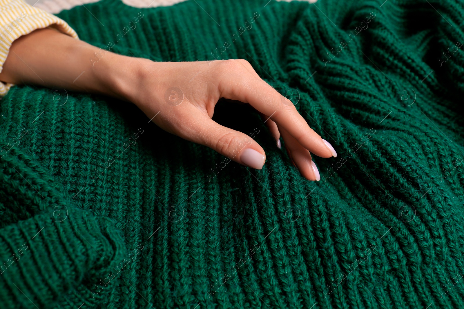 Photo of Woman touching soft green knitted sweater, closeup