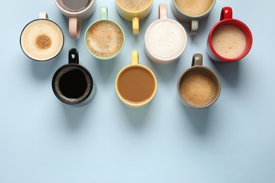 Photo of Many different cups with aromatic coffee on light blue table, flat lay. Space for text
