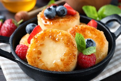 Delicious cottage cheese pancakes with fresh berries and honey on table, closeup