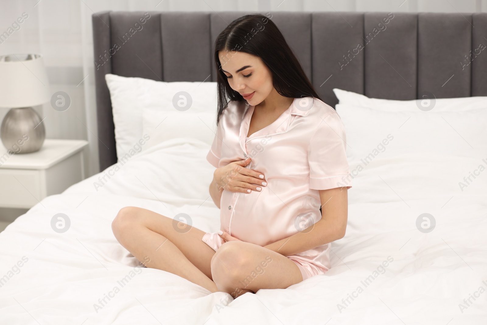 Photo of Pregnant young woman on bed at home