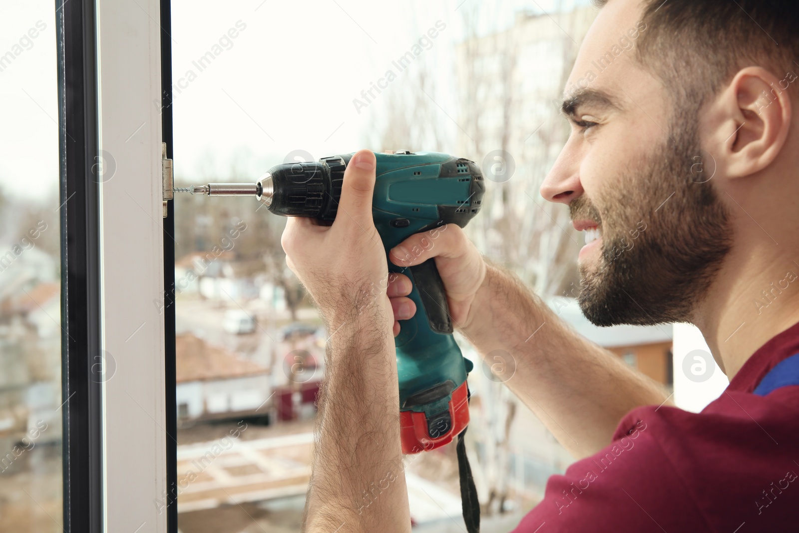 Photo of Construction worker using drill while installing window indoors, closeup