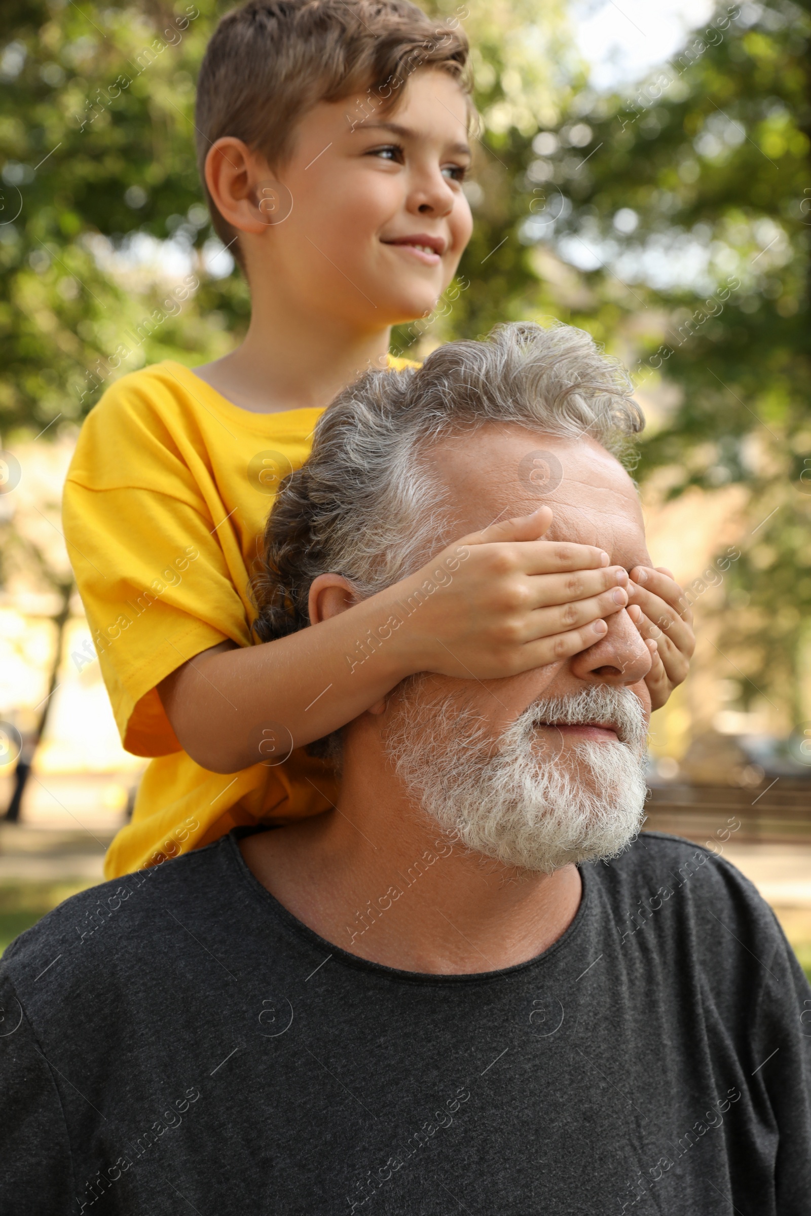 Photo of Senior man with his little grandson having fun together in park