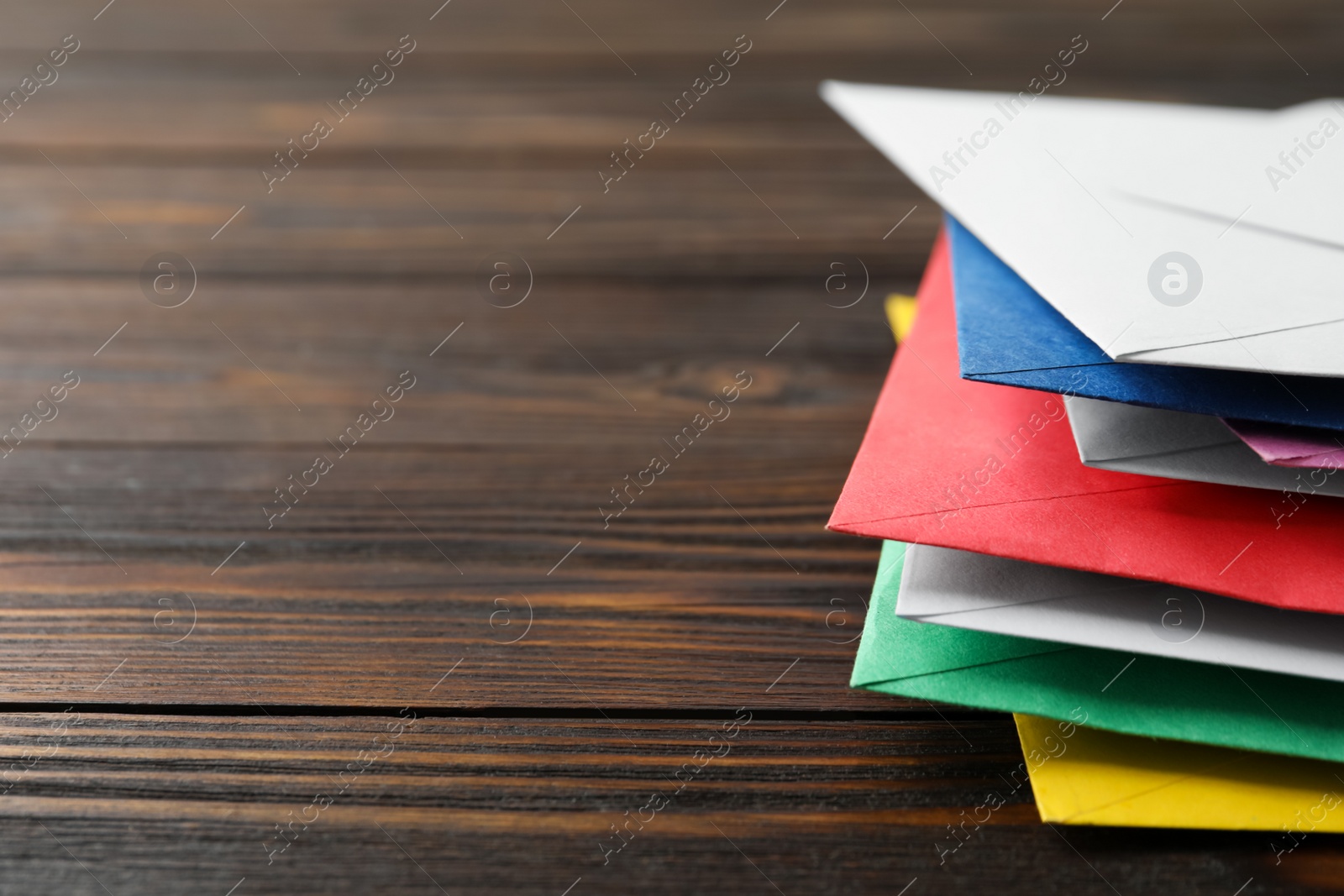 Photo of Colorful paper envelopes on wooden background, closeup. Space for text