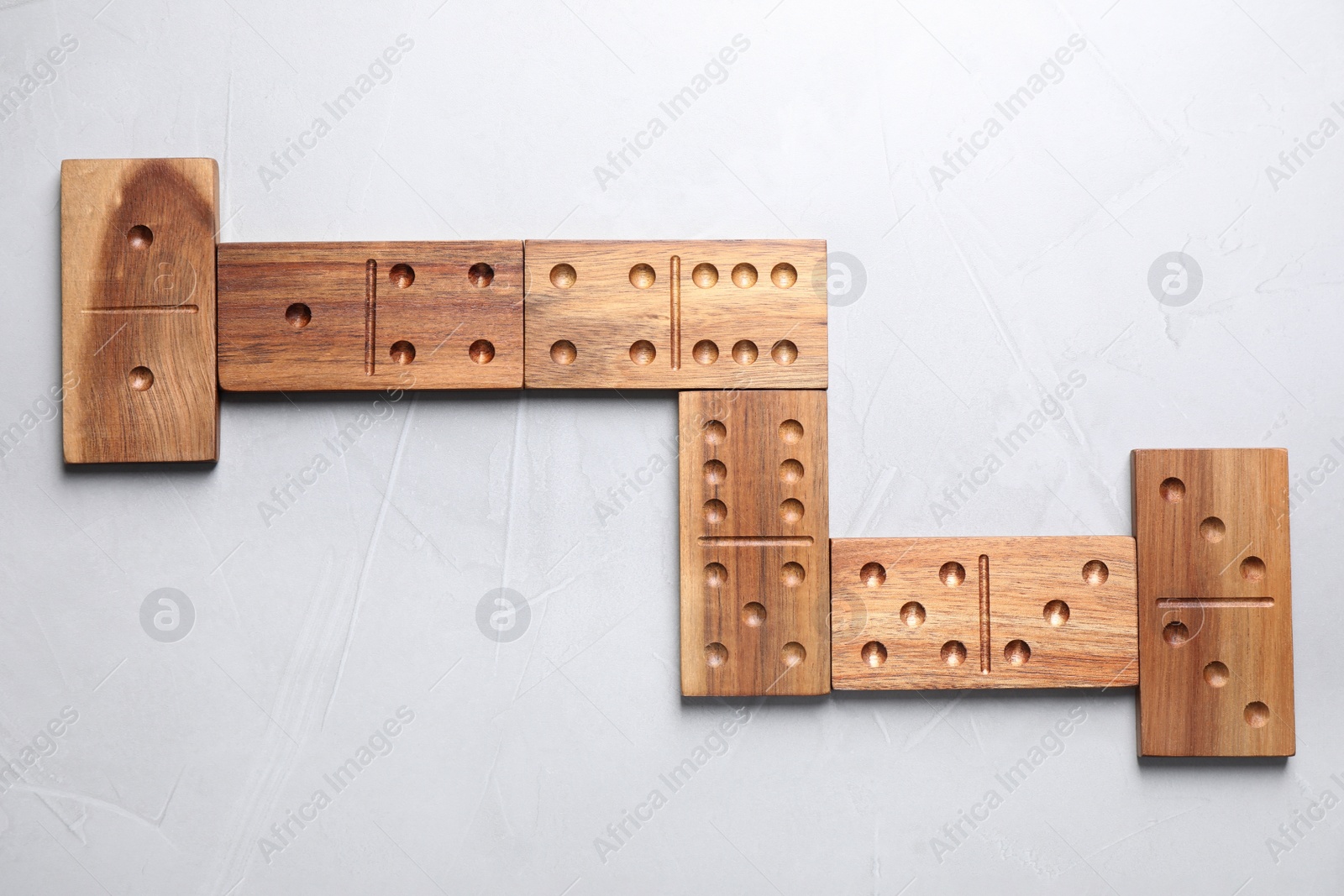 Photo of Wooden domino tiles on light grey table, flat lay