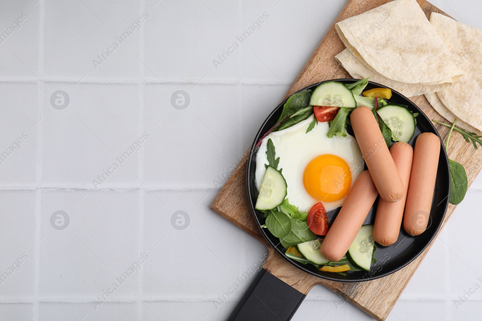 Photo of Delicious breakfast with boiled sausages and fried egg on white tiled table, top view. Space for text