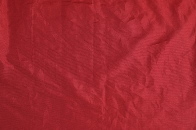 Photo of Crumpled dark red fabric as background, top view