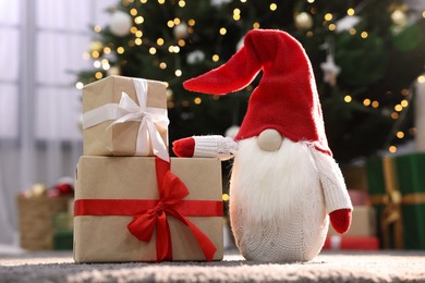 Beautiful gift boxes and Christmas gnome on carpet indoors